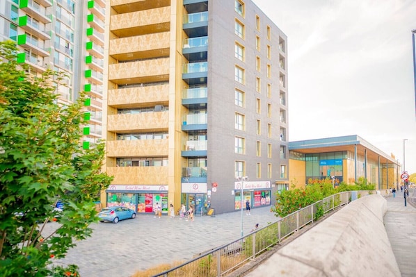 Een modern gebouw met meerdere verdiepingen, een commercieel gedeelte op de begane grond en een voetpad.