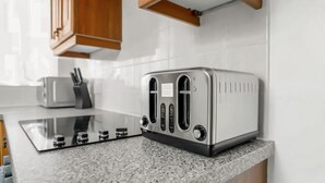 Une cuisine avec un grille-pain en acier inoxydable posé sur un plan de travail en granit, des armoires en bois et une fenêtre au-dessus du plan de travail.