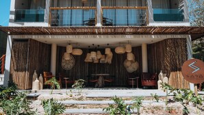 Un edificio moderno con un balcón de dos pisos, muebles de mimbre y un letrero con un logotipo estilizado de 'S'.