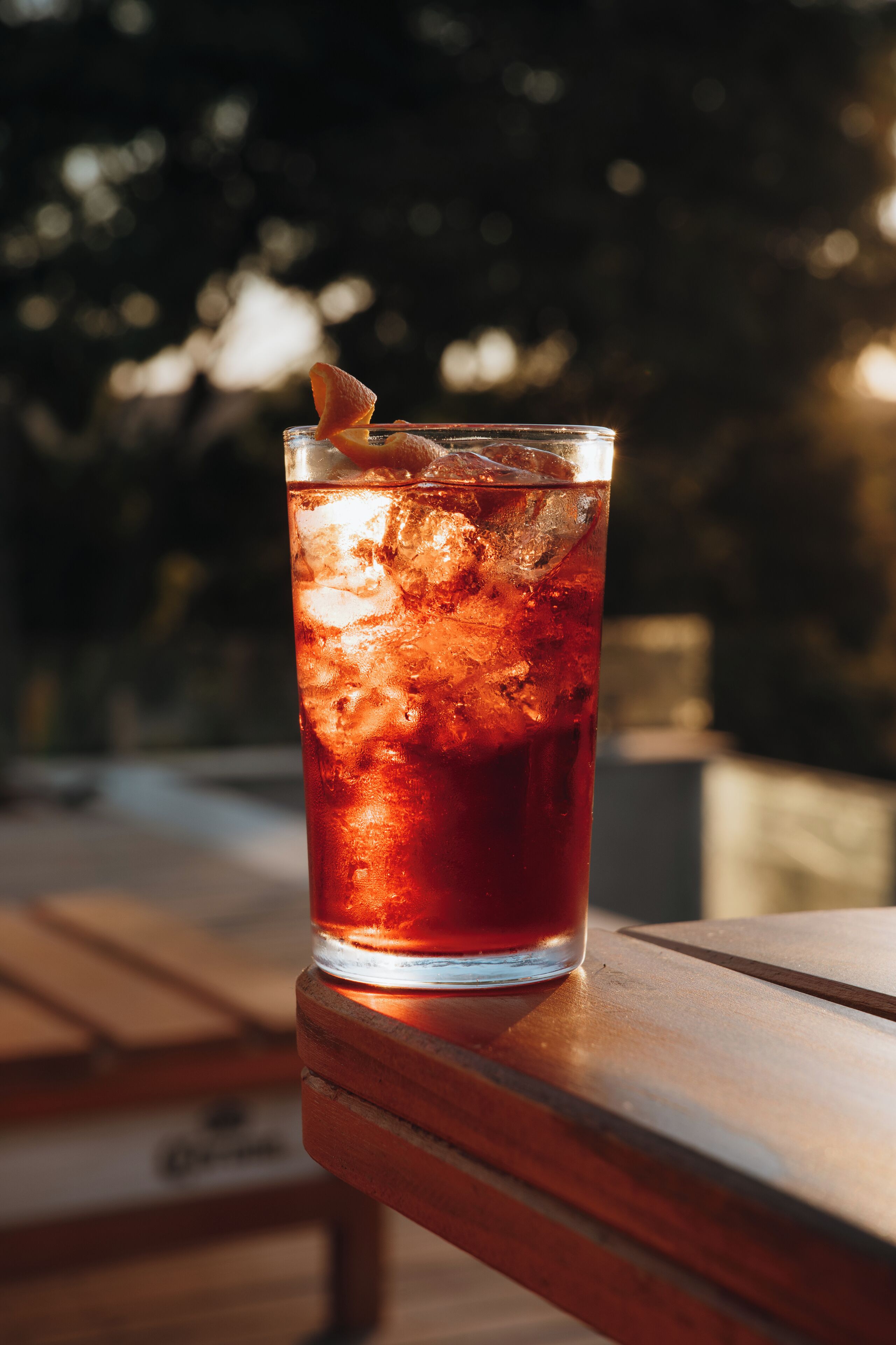 Un vaso de té helado sobre una mesa de madera al aire libre.