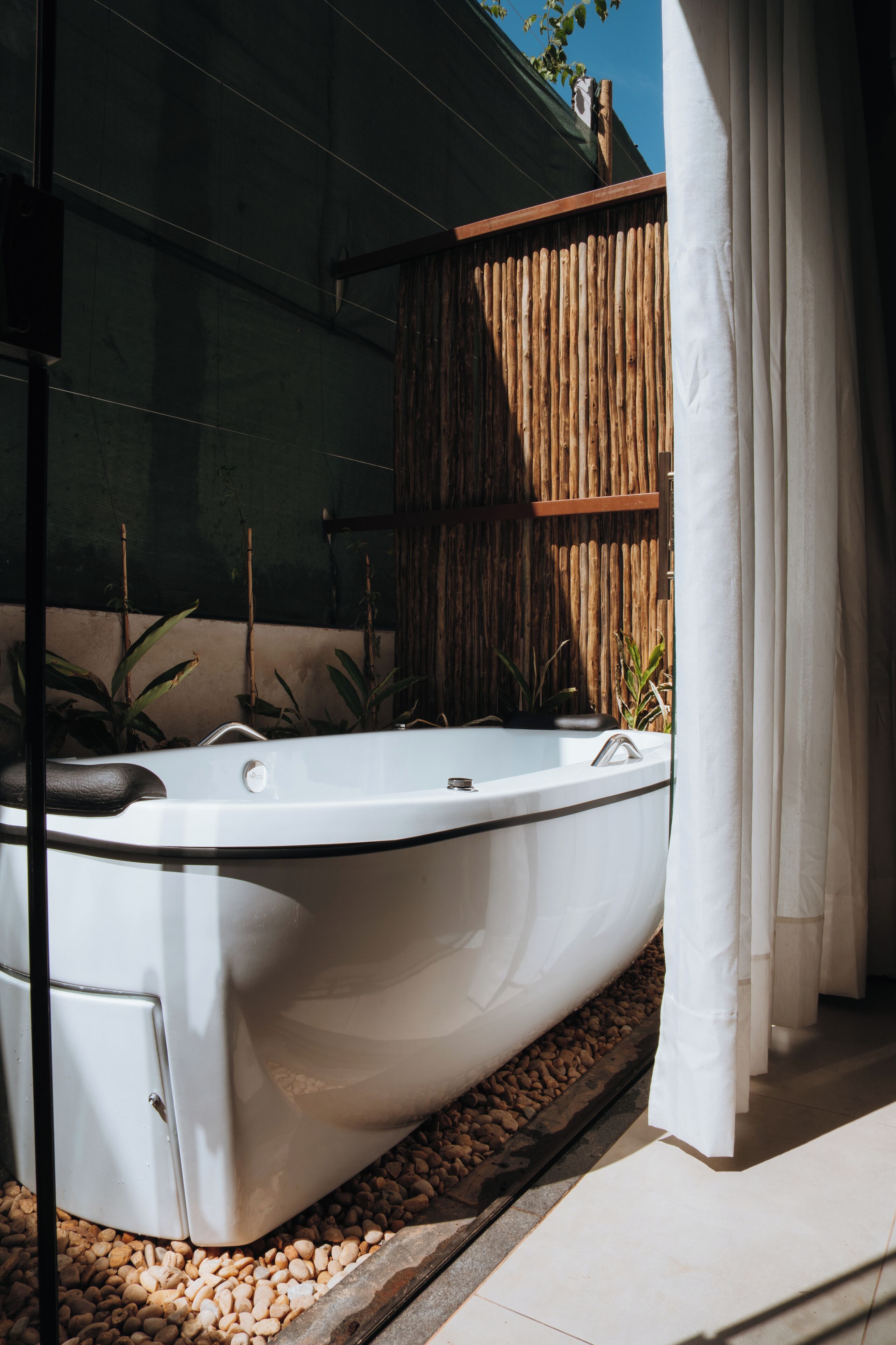 A spa area with a hot tub, bamboo wall, and potted plants.