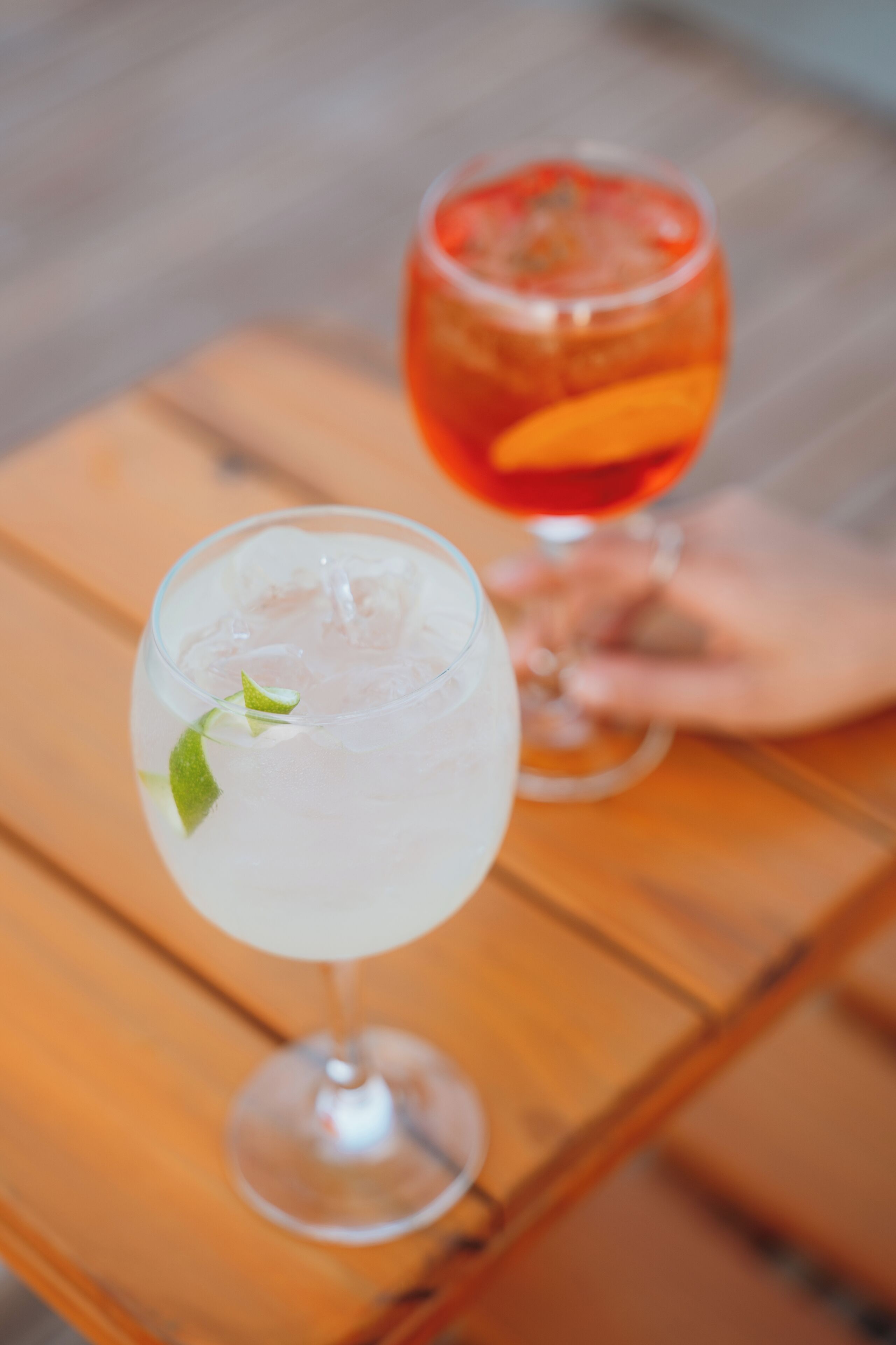 Two glasses of cocktails on a wooden table.