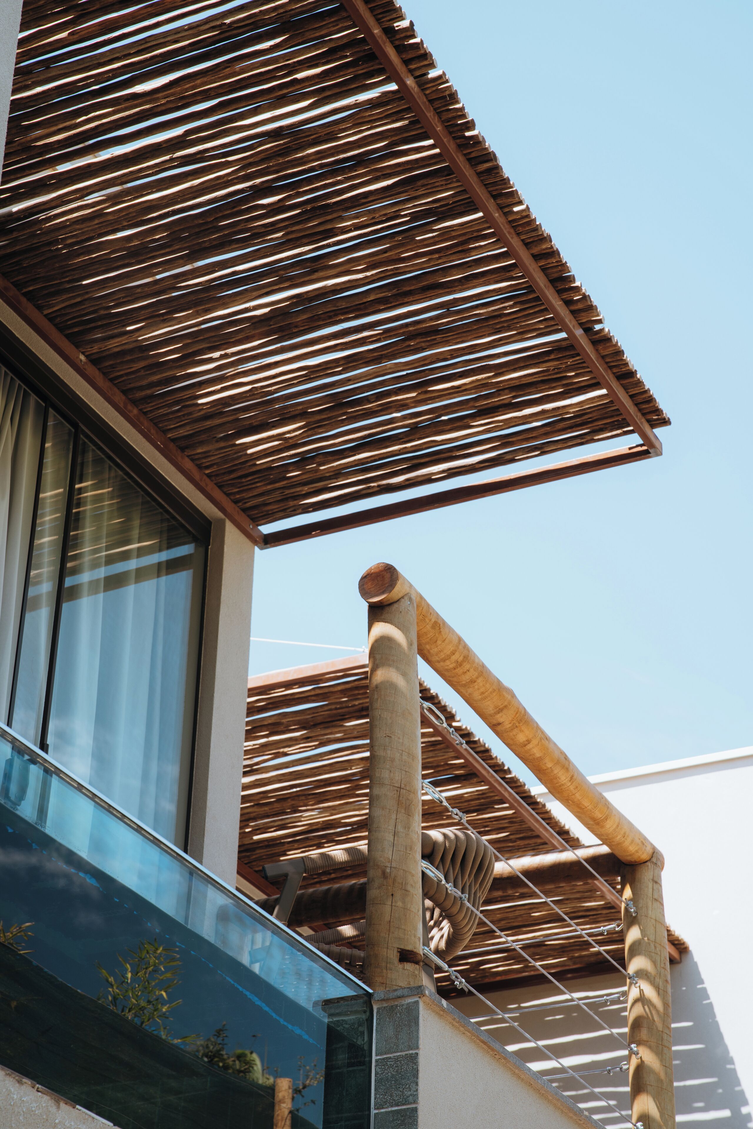 Un edificio moderno con una estructura de pérgola de madera, ventanas amplias y cielo despejado.
