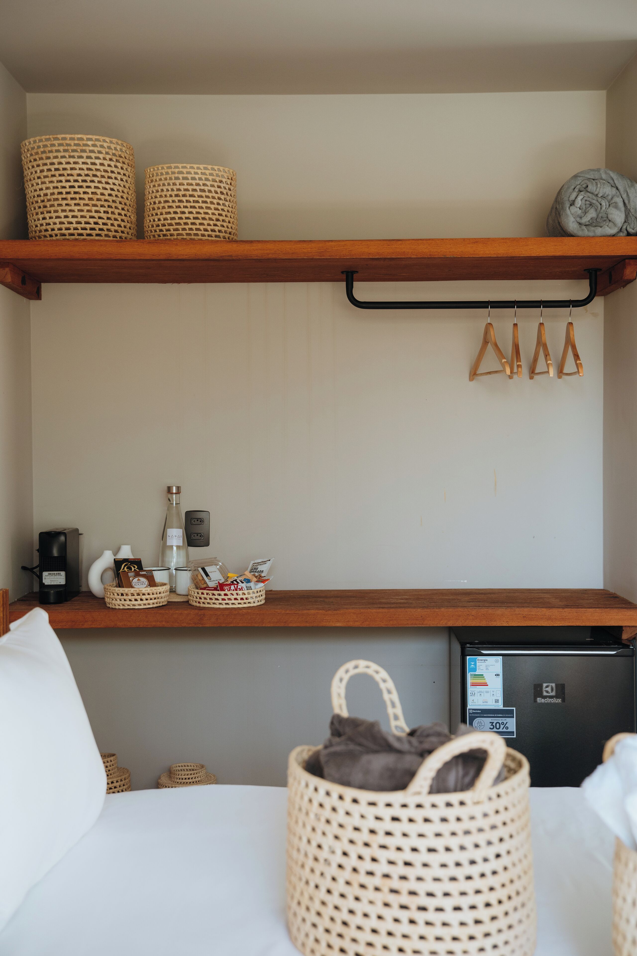 Una kitchenette con cafetera, una botella y una cesta de aperitivos.