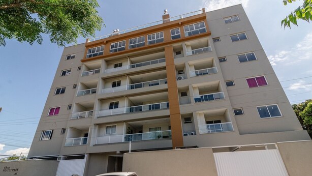 A multi-story residential building with balconies, a garage, and a clear sky. - OBP \- Condomínio Moderno a 600m da Praia (Penha)