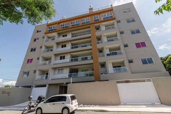 A multi-story residential building with balconies, a garage, and a clear sky. - OBP \- Condomínio Moderno a 600m da Praia (Penha)