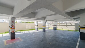 An empty parking garage with concrete pillars, fire extinguishers, and a 'No Parking' sign. - OBP \- Condomínio Moderno a 600m da Praia (Penha)