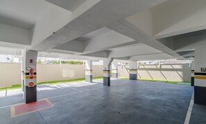 An empty parking garage with concrete pillars, fire extinguishers, and a 'No Parking' sign. - OBP \- Condomínio Moderno a 600m da Praia (Penha)