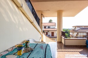 Ein Balkon mit Fliesenboden, weißer Wand und Geländer.