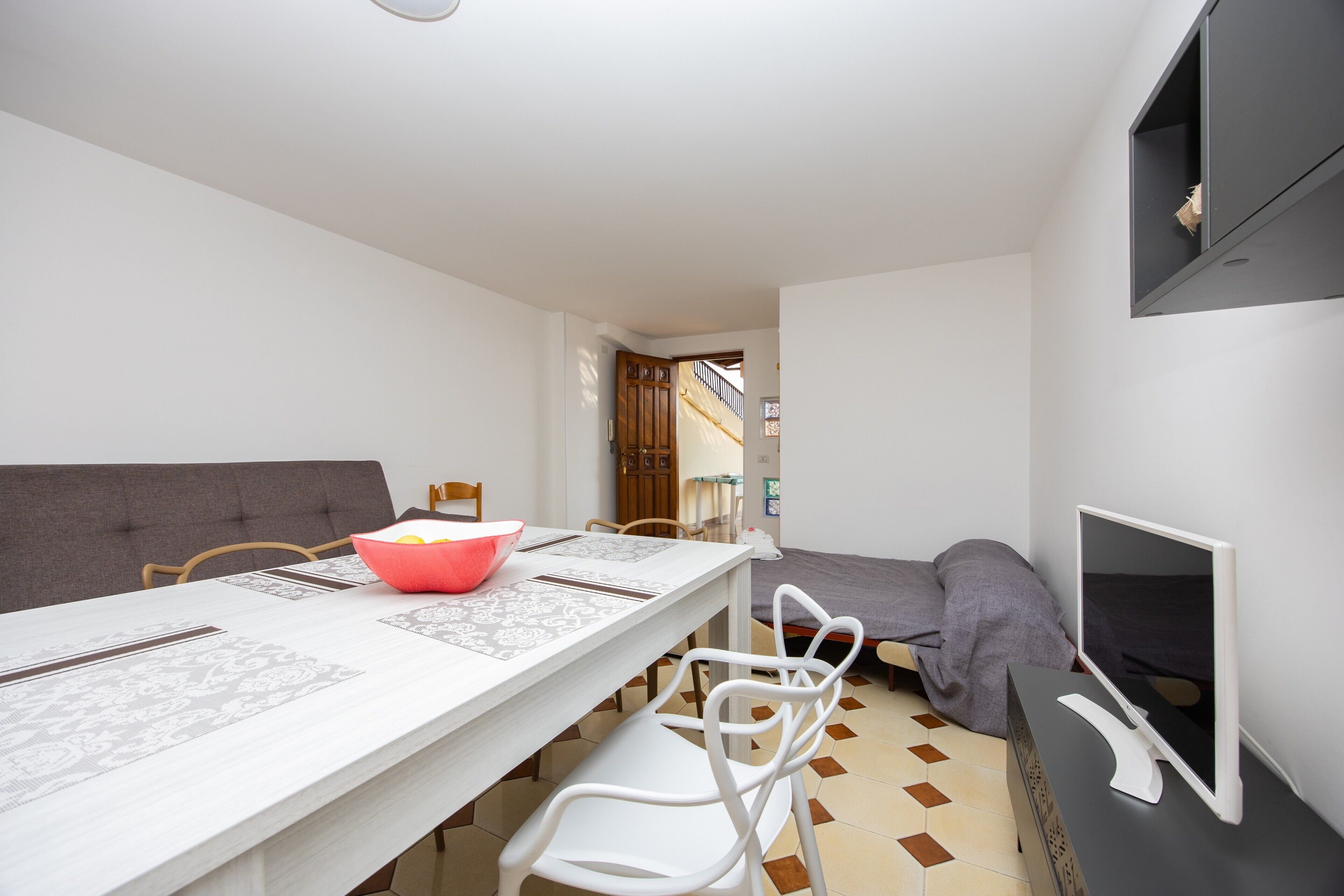 Une pièce de taille modeste comprenant une table à manger, des chaises, un lit et un téléviseur.