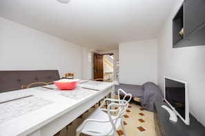 A compact room with a dining table, chairs, a bed, and a TV. - Apartment 'Casa Artale' with Shared Terrace and Air Conditioning (Capo d'Orlando)