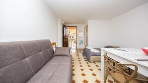 Quarto moderno com sofá, mesa de jantar com cadeiras e piso estampado.
