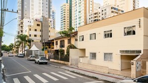 Una vista di strada con edifici residenziali a più piani, un attraversamento pedonale e auto parcheggiate.
