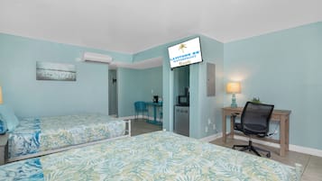 A hotel room with two beds, a desk, a chair, a TV, and a sign indicating it's a Latitude 26 Waterfront Resorts location.
