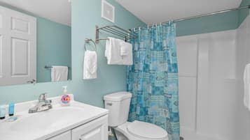 Ein Badezimmer mit einem weißen Waschbecken, einer Toilette und einem blauen, gemusterten Duschvorhang.