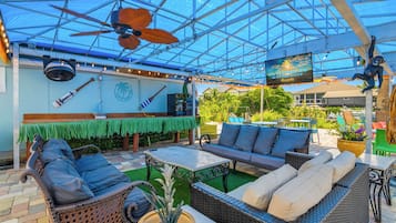 An outdoor patio with wicker furniture, a ceiling fan, and a sign indicating a waterfront location.