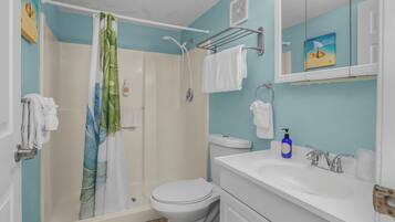 A bathroom with a shower, toilet, sink, and a towel rack.