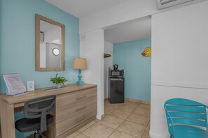 A hotel room with a desk, chair, and a microwave. - Tropical King Studio in Fort Myers Beach (Fort Myers Beach)