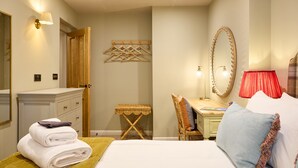 A neatly arranged bedroom with a bed, bedside table, chair, and a small desk with a mirror. - The Dovecote (Matlock)