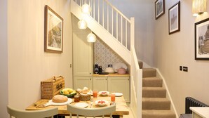 A dining area with a wooden table, chairs, and a staircase leading to an upper level. - The Dovecote (Matlock)