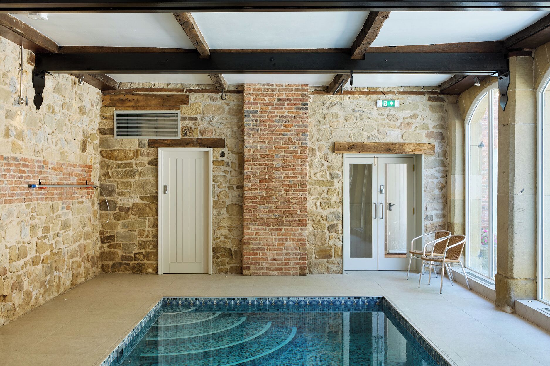 A pool area with stone walls, wooden beams, and a tiled floor.