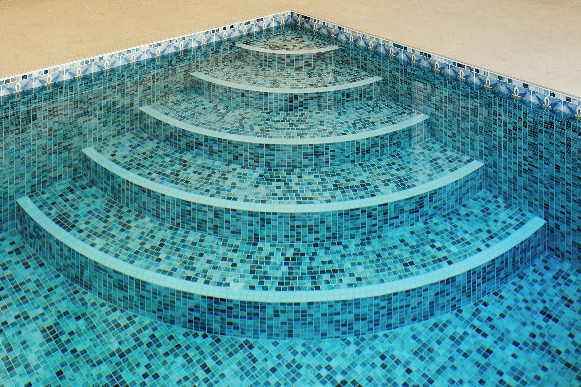 A multi-tiered infinity pool with a blue mosaic design.
