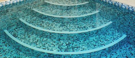 A multi-tiered infinity pool with a blue mosaic design.