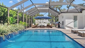 A covered swimming pool with lounge chairs and a barbecue area. - Bimini Breeze - Updated Island Retreat with Pool & Beach Access (West Palm Beach)