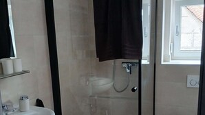 Une salle de bain moderne avec une douche à parois de verre, un lavabo blanc et des toilettes.