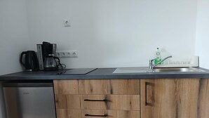 Une cuisine équipée d’un lave-vaisselle Bosch, de meubles en bois, d’un évier avec un robinet et d’une machine à café.