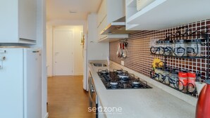 A kitchen with white cabinets, a gas stove, and a spice rack with jars. - 3BR apt Near Beach w/ Garage in Picarras Nra0490 (Picarras)