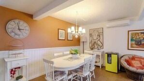 A dining area with a white table, chairs, a clock, and wall art. - 3BR apt Near Beach w/ Garage in Picarras Nra0490 (Picarras)