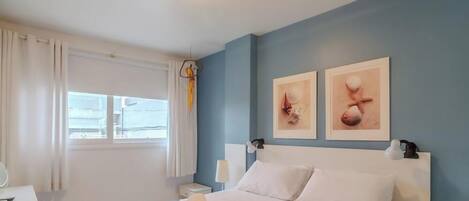 Una habitación de hotel con una cama, una mesita de noche, una lámpara y dos obras de arte colgadas en la pared.