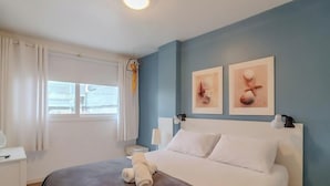 Ein Schlafzimmer mit einem Bett, einem Nachttisch, einer Lampe und zwei gerahmten Bildern an der Wand.