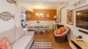 A living room with a sofa, a dining table with chairs, a TV, and a fireplace. - 3BR apt Near Beach w/ Garage in Picarras Nra0490 (Picarras)