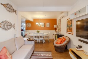 Un soggiorno con divano, tavolo da pranzo con sedie, televisione e camino.