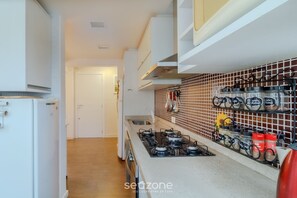Una cucina con mobili bianchi, un fornello a gas e un ripiano per spezie con barattoli.