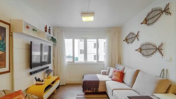 A modern living room with a flat-screen TV, sofa, and decorative fish wall art. - 3BR apt Near Beach w/ Garage in Picarras Nra0490 (Picarras)