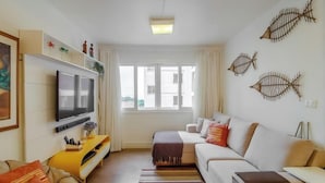 Ein modernes Wohnzimmer mit Fernseher, Sofa und dekorativer Fischwandkunst.