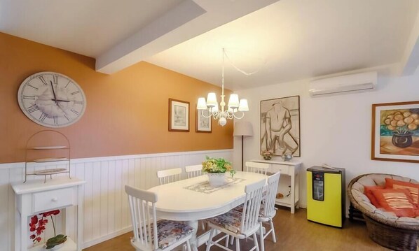 A dining area with a white table, white chairs, a clock, and a chandelier. - 3BR apt Near Beach w/ Garage in Picarras Nra0490 (Picarras)