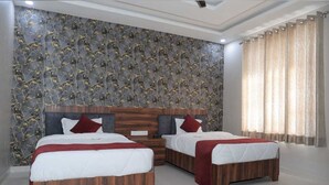 A modern bedroom with two beds, a stone-patterned wall, and a large window with curtains. - Hotel Om Palace (Jaipur)