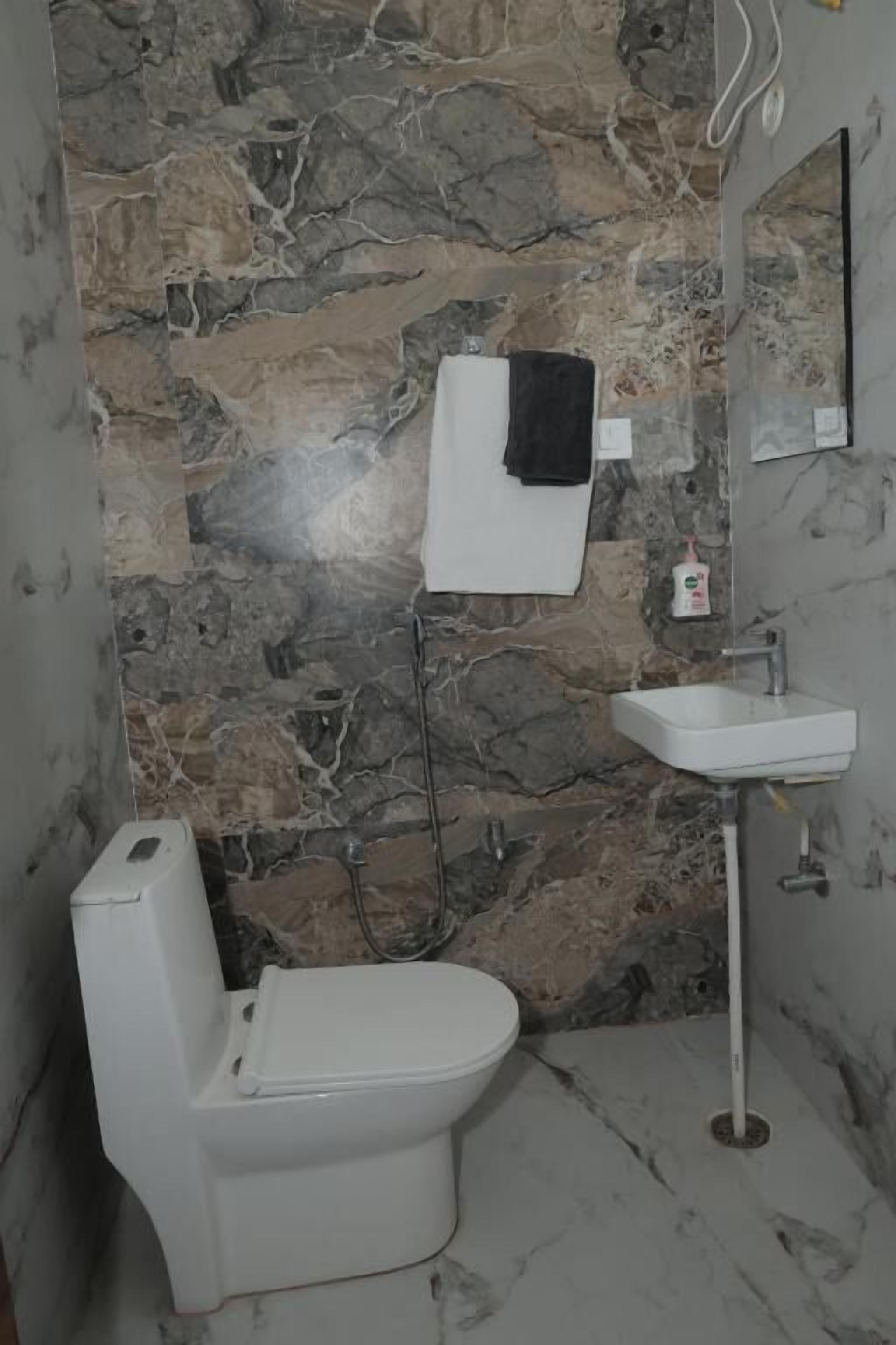 Een badkamer met een wit toilet, een witte wastafel en een spiegel.