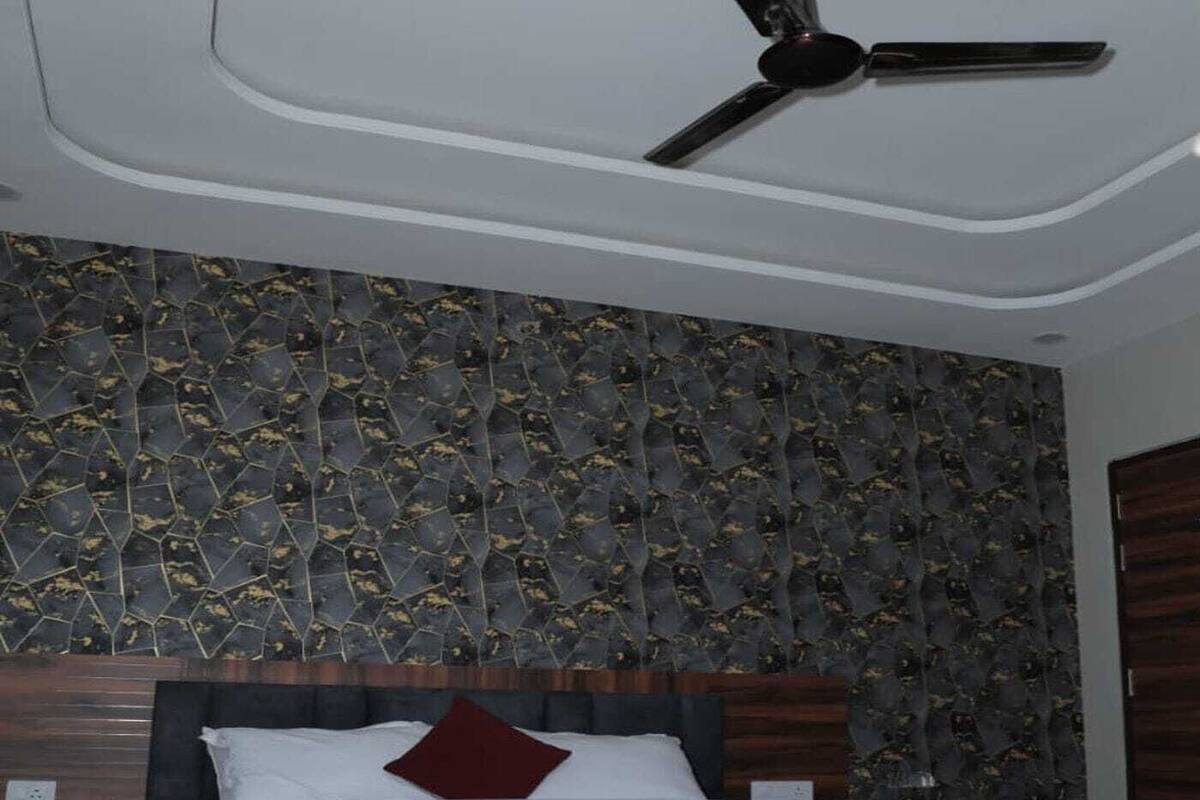 Une chambre à coucher avec un lit, un ventilateur de plafond et un mur décoré de motifs.