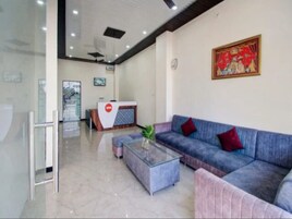 Un área de recepción moderna con un mostrador, un sofá azul, una mesa de centro de vidrio y un cuadro colgado en la pared.