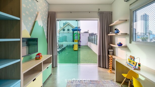 Ein zeitgemäßer Spielraum für Kinder mit Fernseher, Regalen und Blick auf einen Spielplatz im Freien.