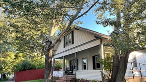 A two-story house with a porch, a red fence, and a large tree in front. - Glenrock Cottage -  charming 4-bedroom house in Glenrock WY (Glenrock)