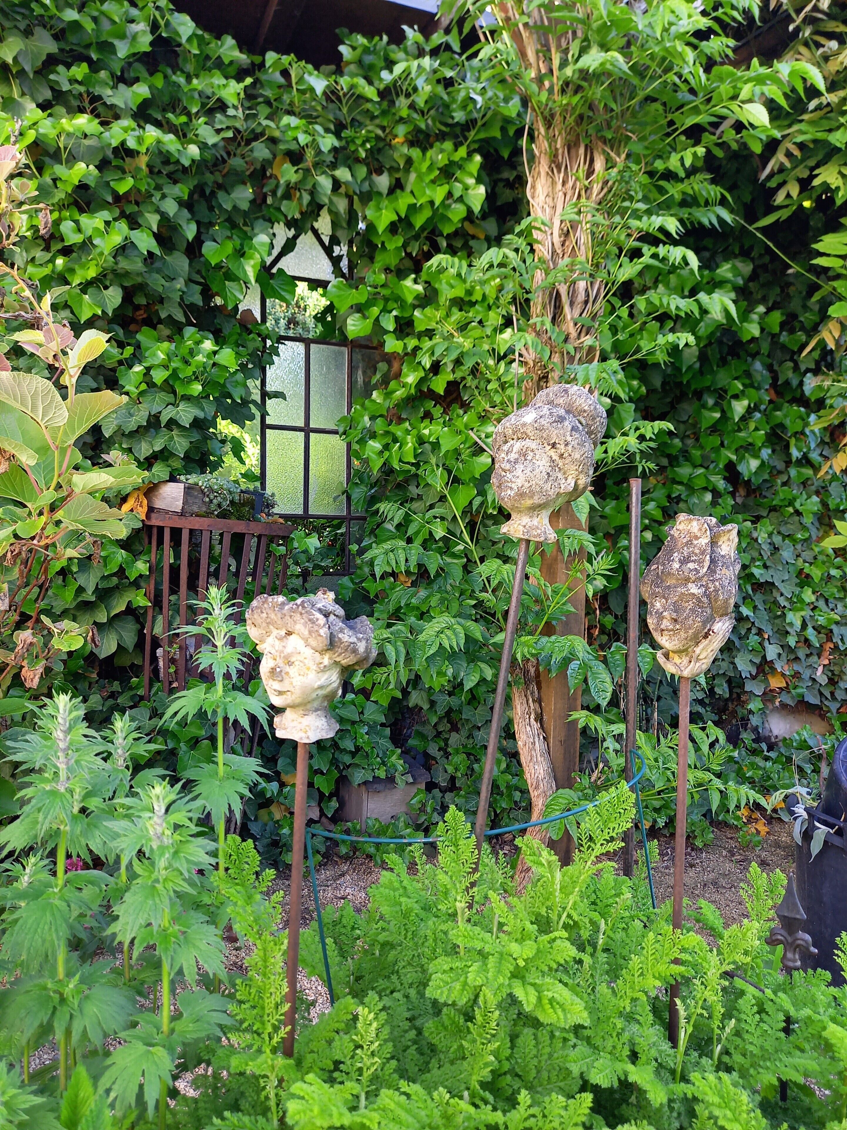 Ein Garten mit unterschiedlichen Pflanzen, einem Holzzaun und einer dekorativen Steinstruktur.