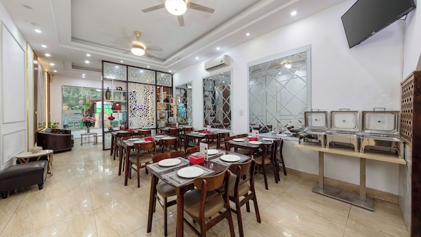 Un espace de restauration bien éclairé, avec plusieurs tables, des chaises et un buffet.