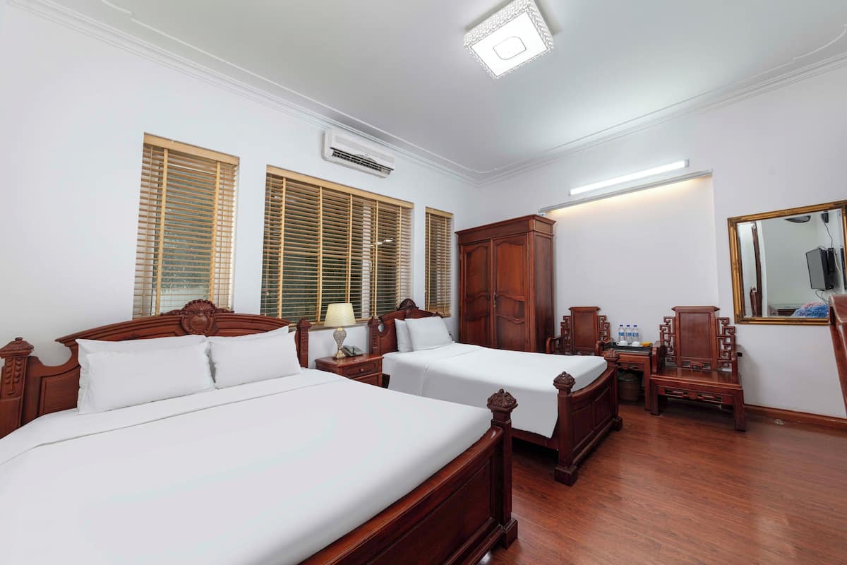 A hotel room with two wooden beds, a wardrobe, a mirror, and a nightstand.