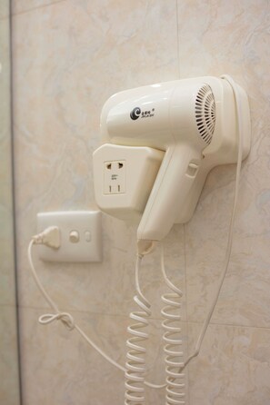 A hair dryer mounted on a wall with a power outlet and a coiled cord. - Hanoi Phoenix Premium Hotel (hoan kiem)
